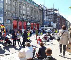 Das Foto zeigt die Menschen auf der Mahnwache. Inklusive Deutschlandfahne und im Hintergrund den Caravan von Kai